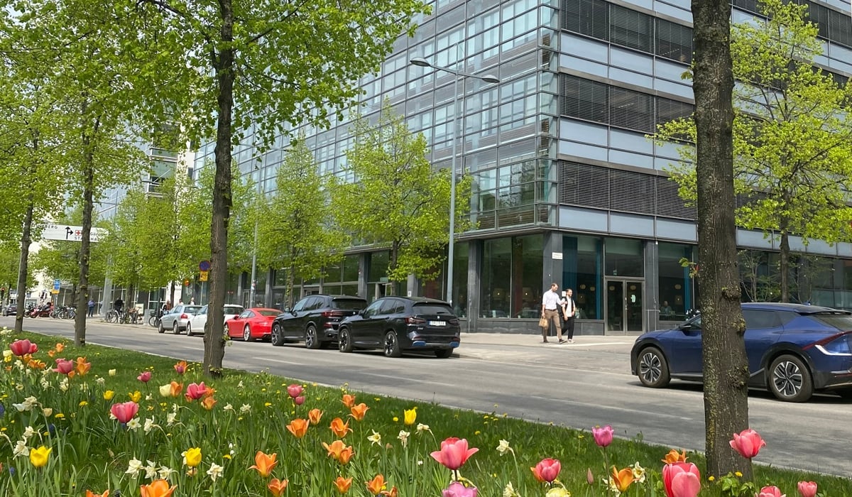 En stadsgata med bilar parkerade framför en hög byggnad.