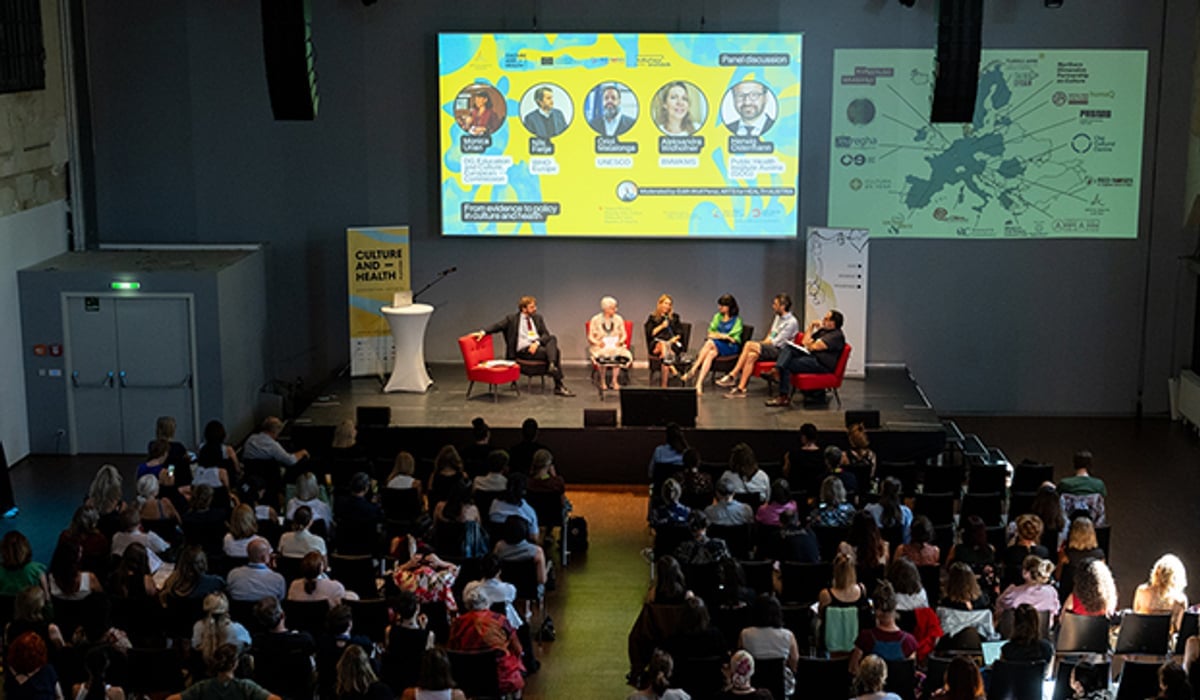 Panel på scen framför stor publik.