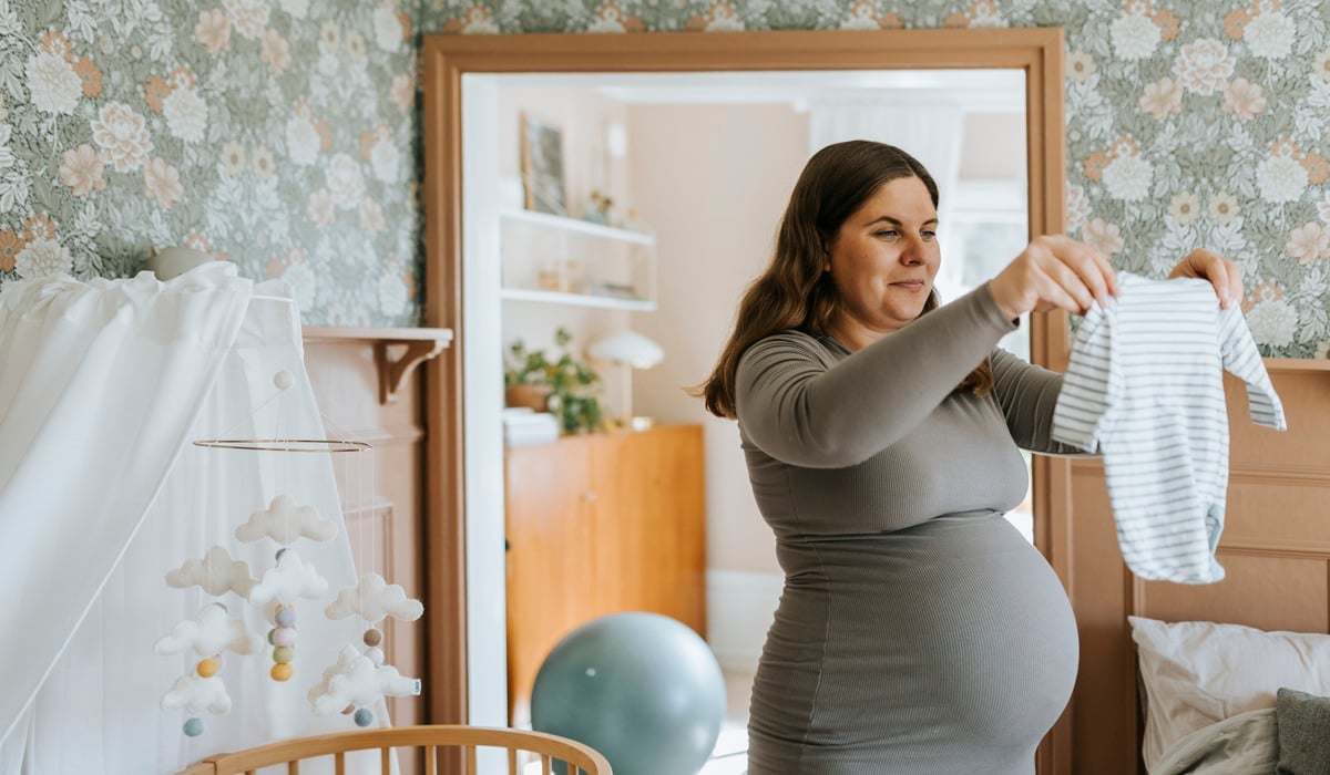 En kvinna i grå klänning som håller i en vit skjorta.