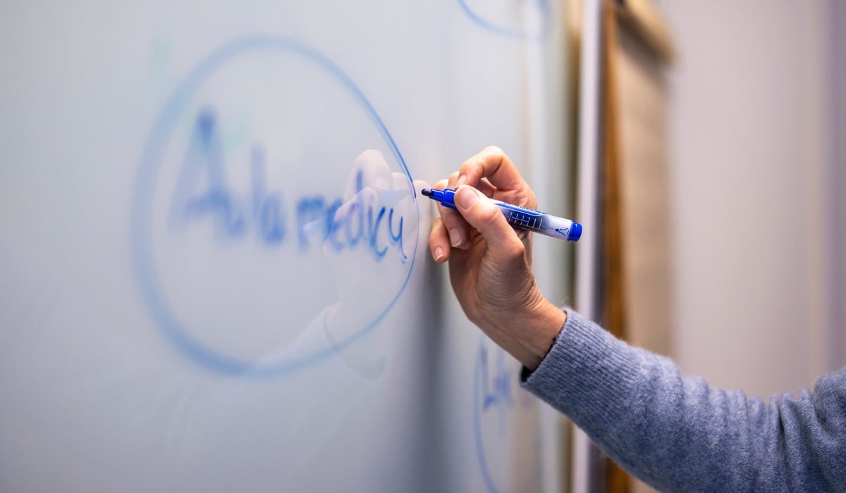 Någon skriver på en whiteboard.