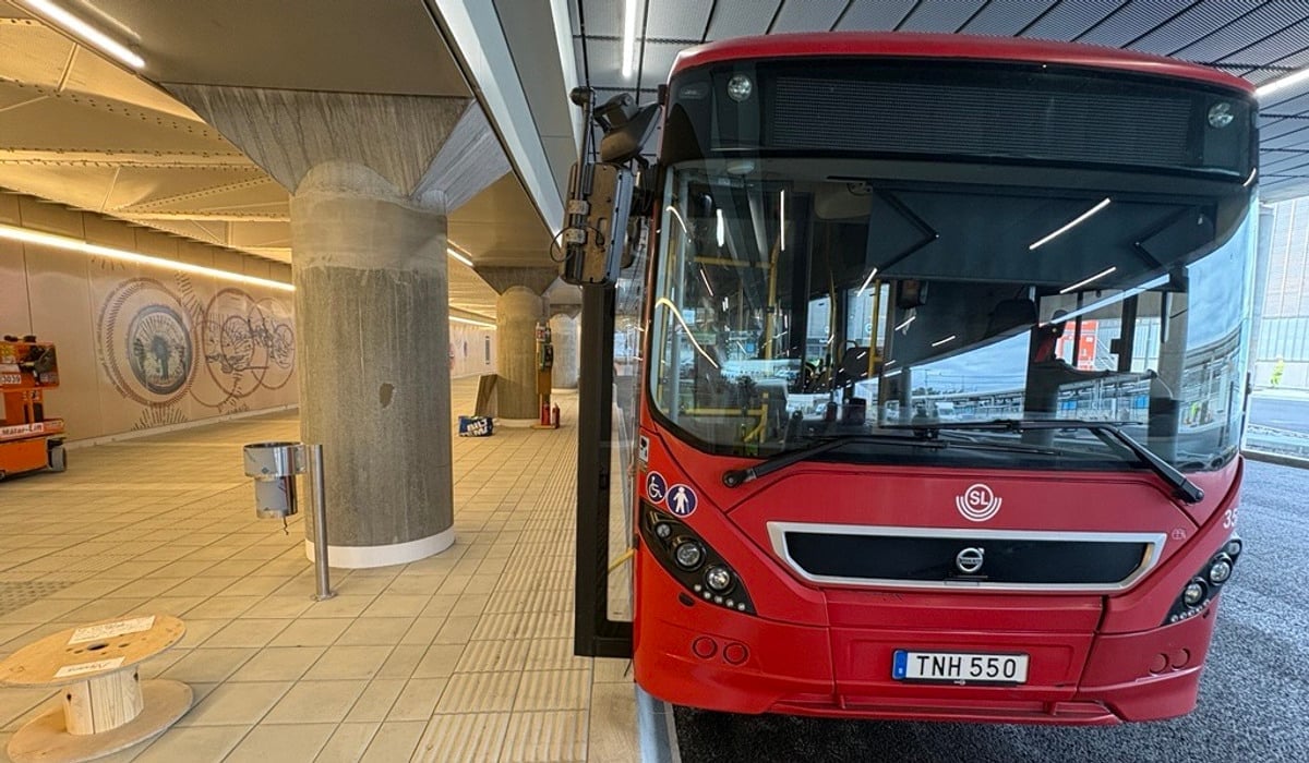 En röd buss som står parkerad vid en busshållplats.