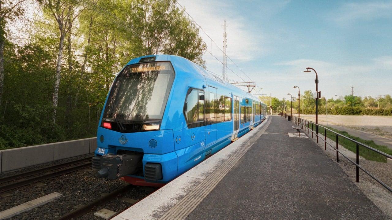 Ett modernt blått tåg som står på perrongen i väntan på avgång.
