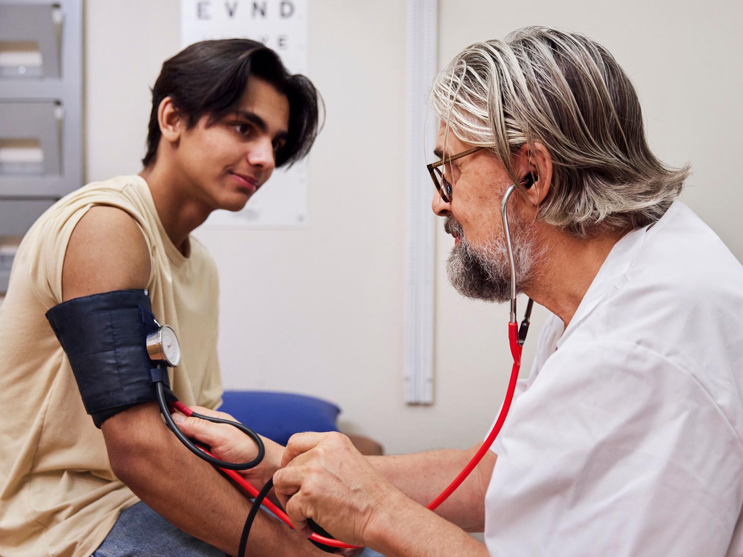 En läkare kollar blodtrycket på en ung person.