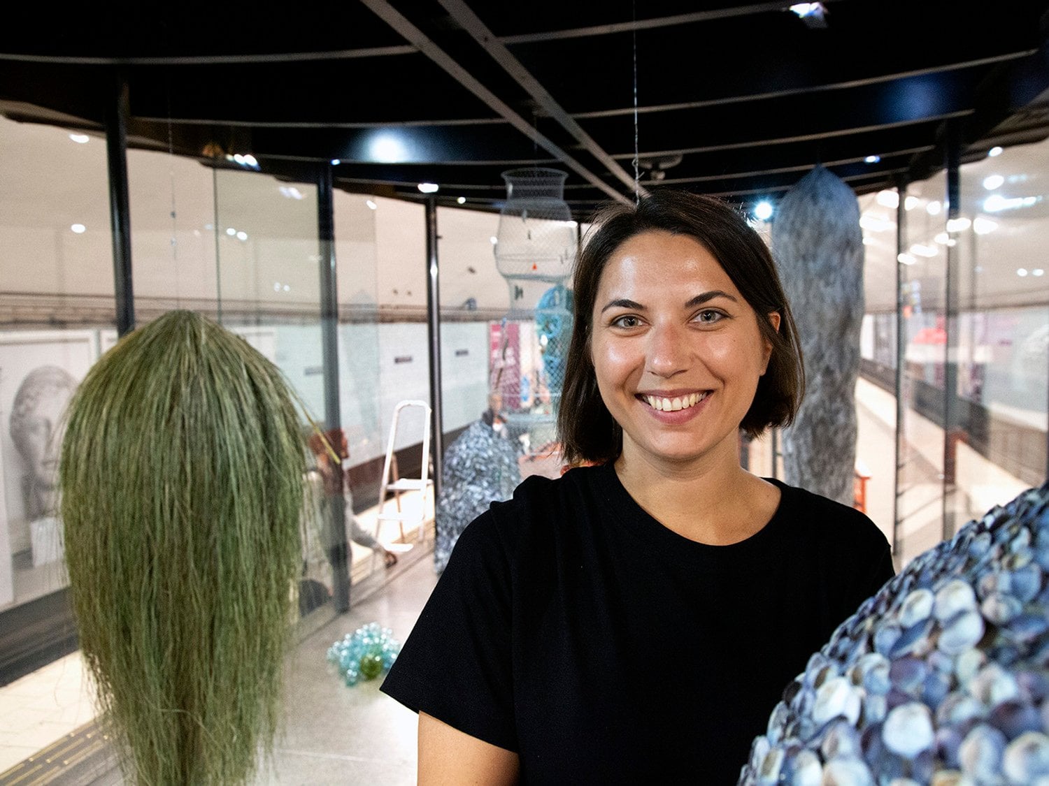 Kvinna som ler mot kameran med flera färgglada konstverk runt sig