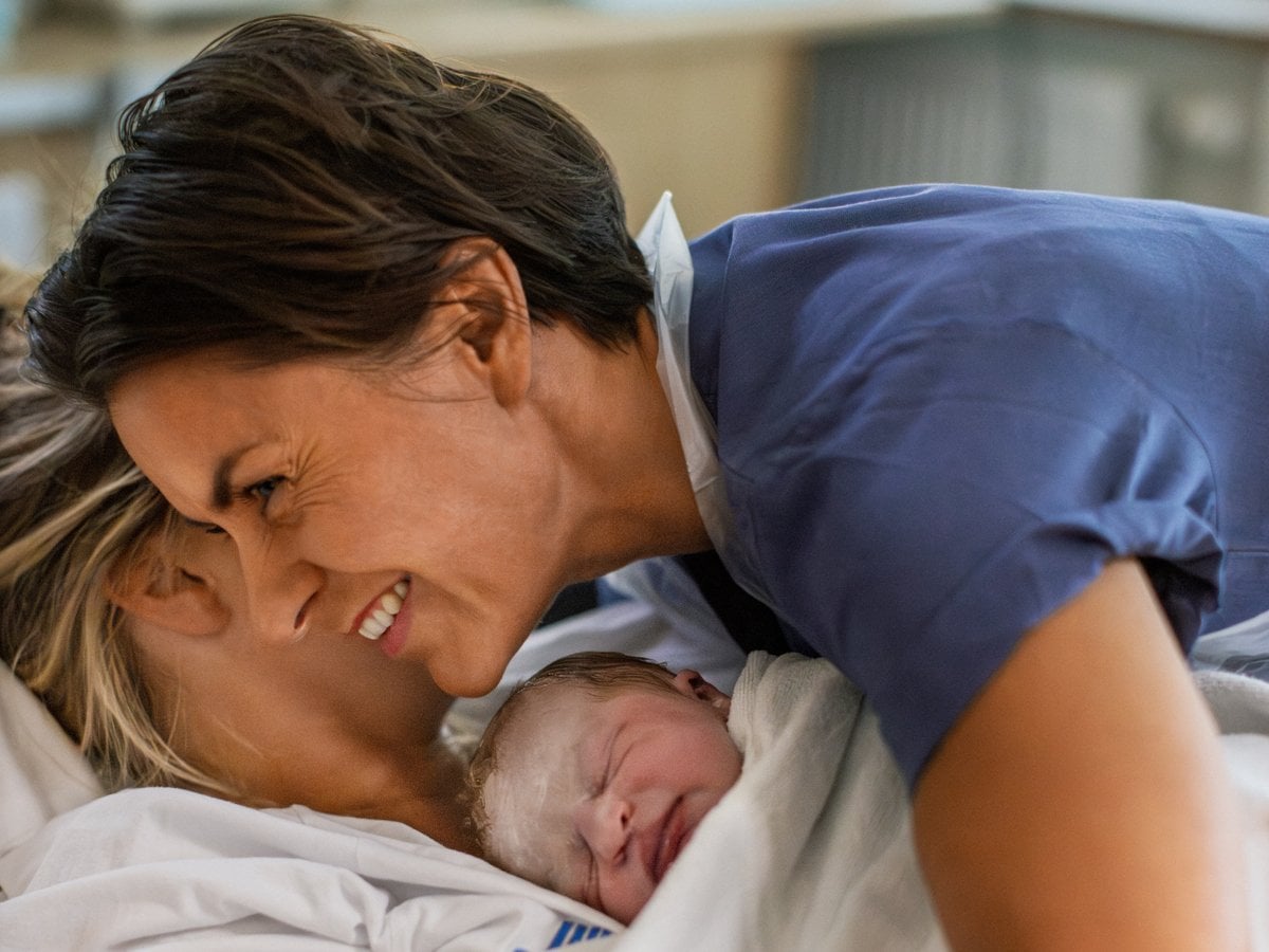 En kvinna håller en baby insvept i en filt.