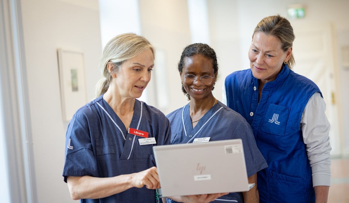 En grupp sjuksköterskor som står runt en bärbar dator.