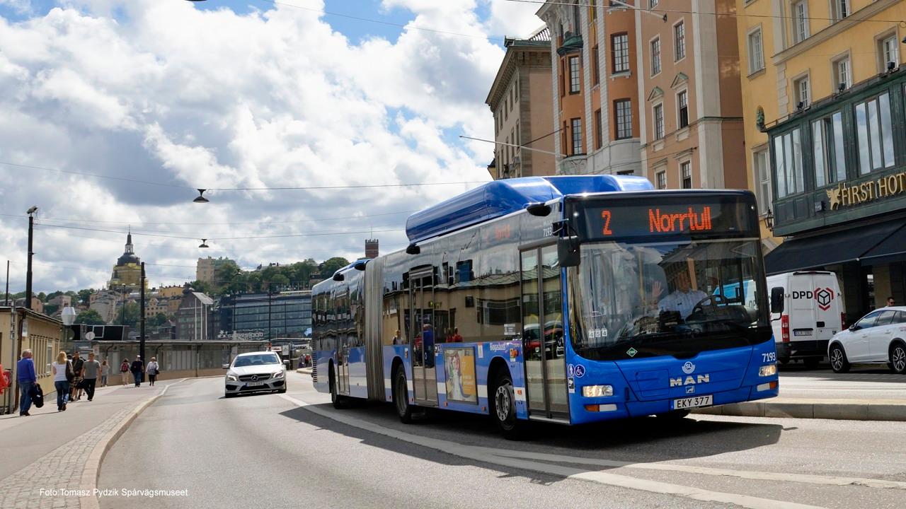 En blå stadsbuss åker förbi skeppsbron i ett soligt Stockholm