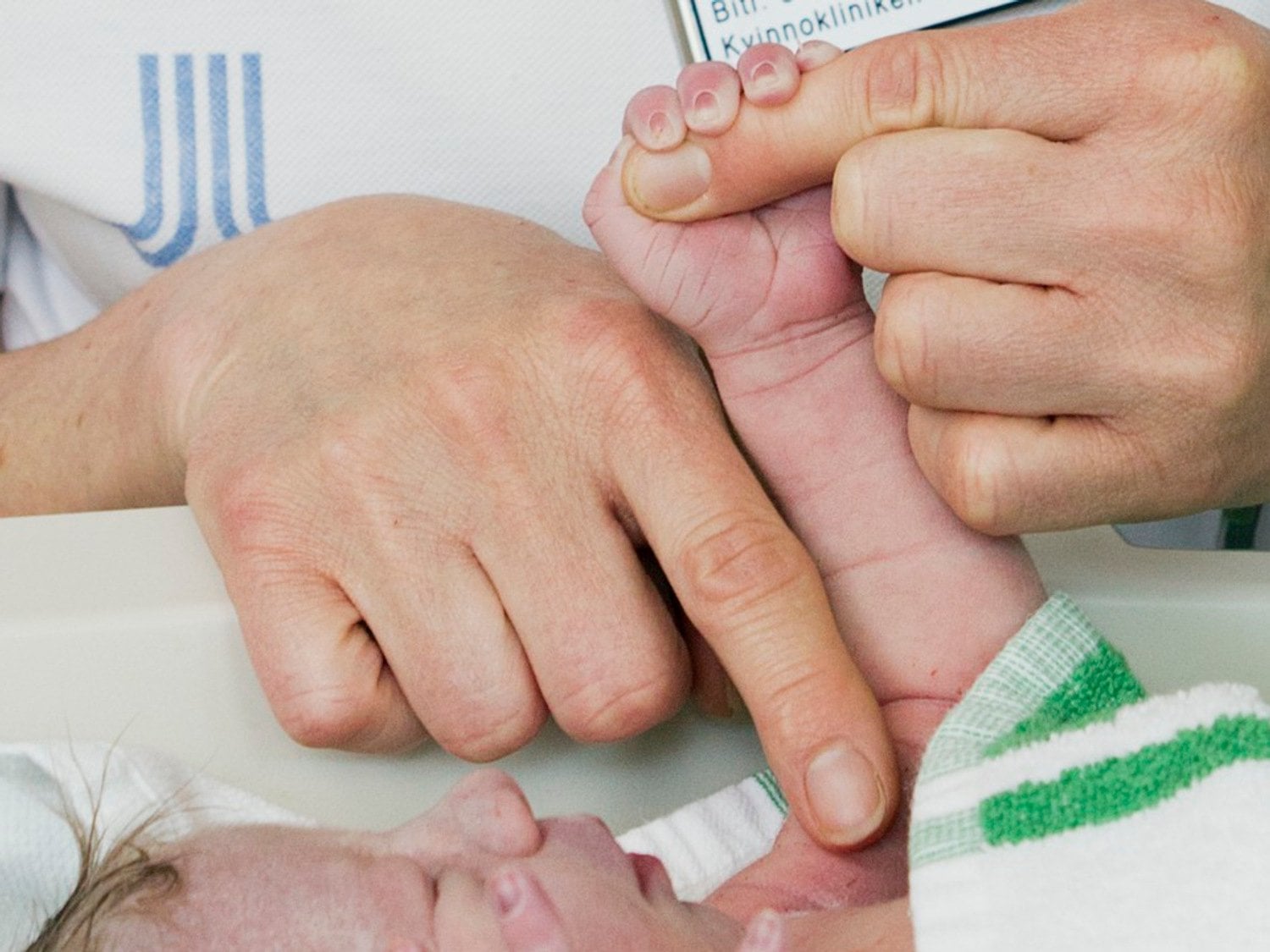 Ett nyfött barn håller i en vuxen persons händer
