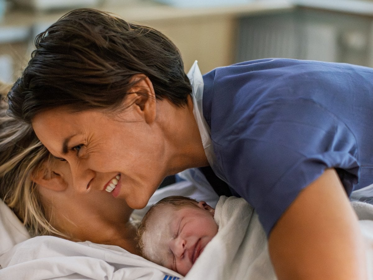 En kvinna håller en baby insvept i en filt.