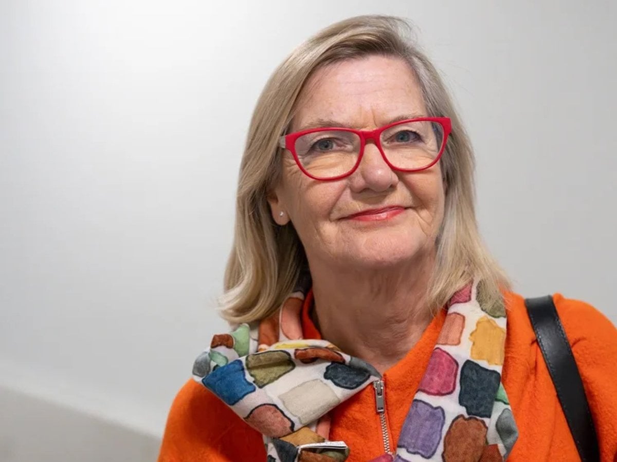 Lotti Helström bär röda glasögon och en färgglad scarf.