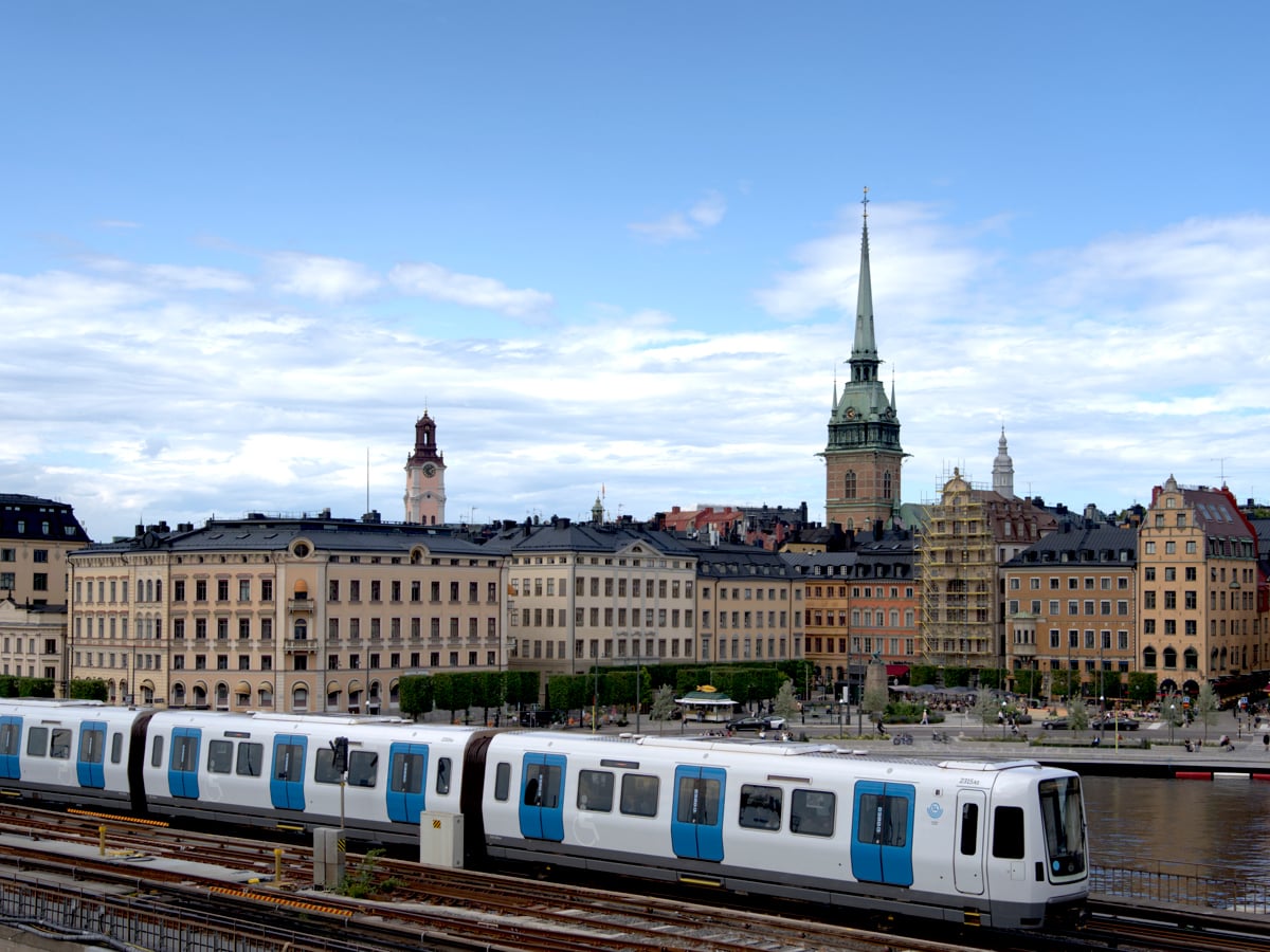 Ett vitt och blått C30-tåg som färdas på en bro förbi Gamla stan.