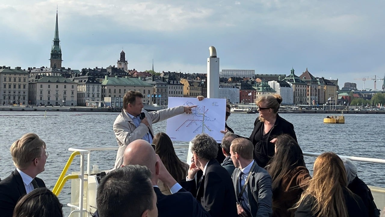 Två personer föreläser för en samling representanter från EU. De befinner sig på en båt och det verkar blåsa en hel del.