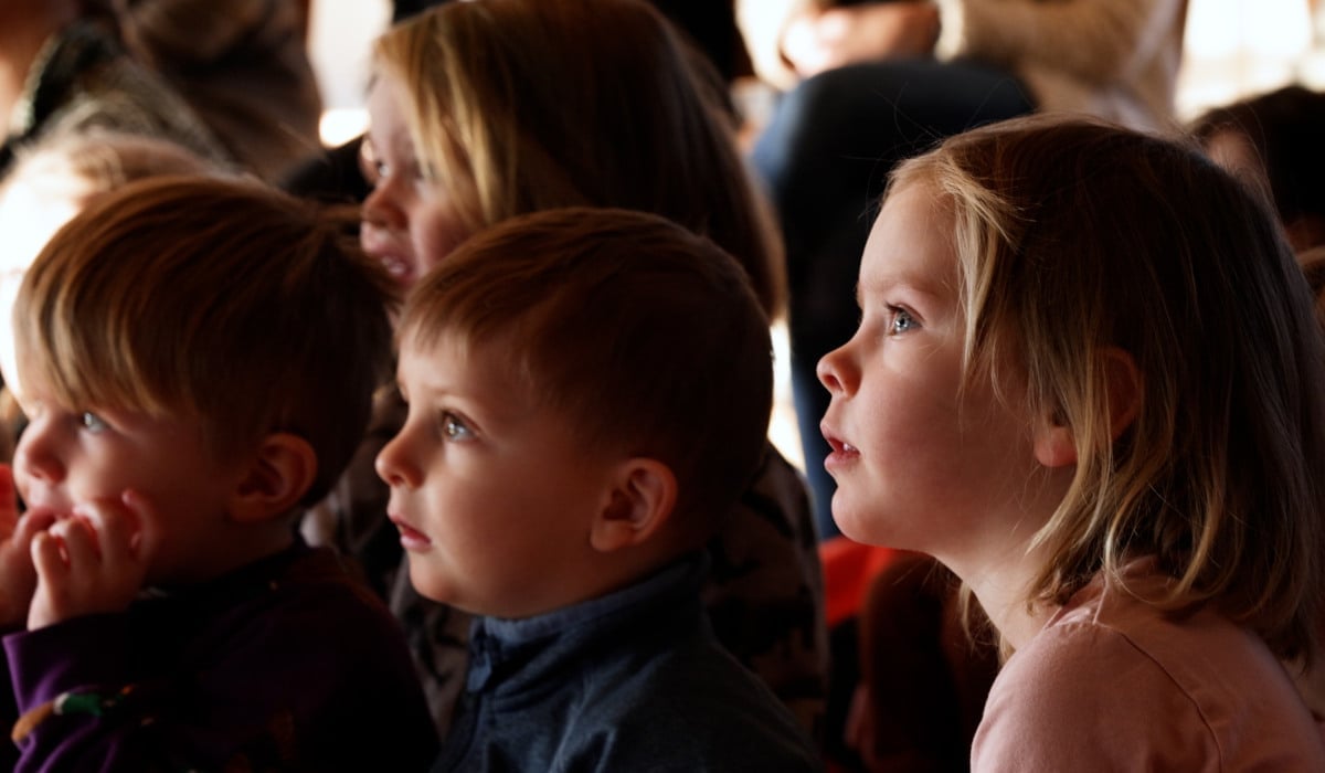 Barn som sitter och tittar koncentrerat åt samma håll (föreställningen de tittar på är utanför bilden)