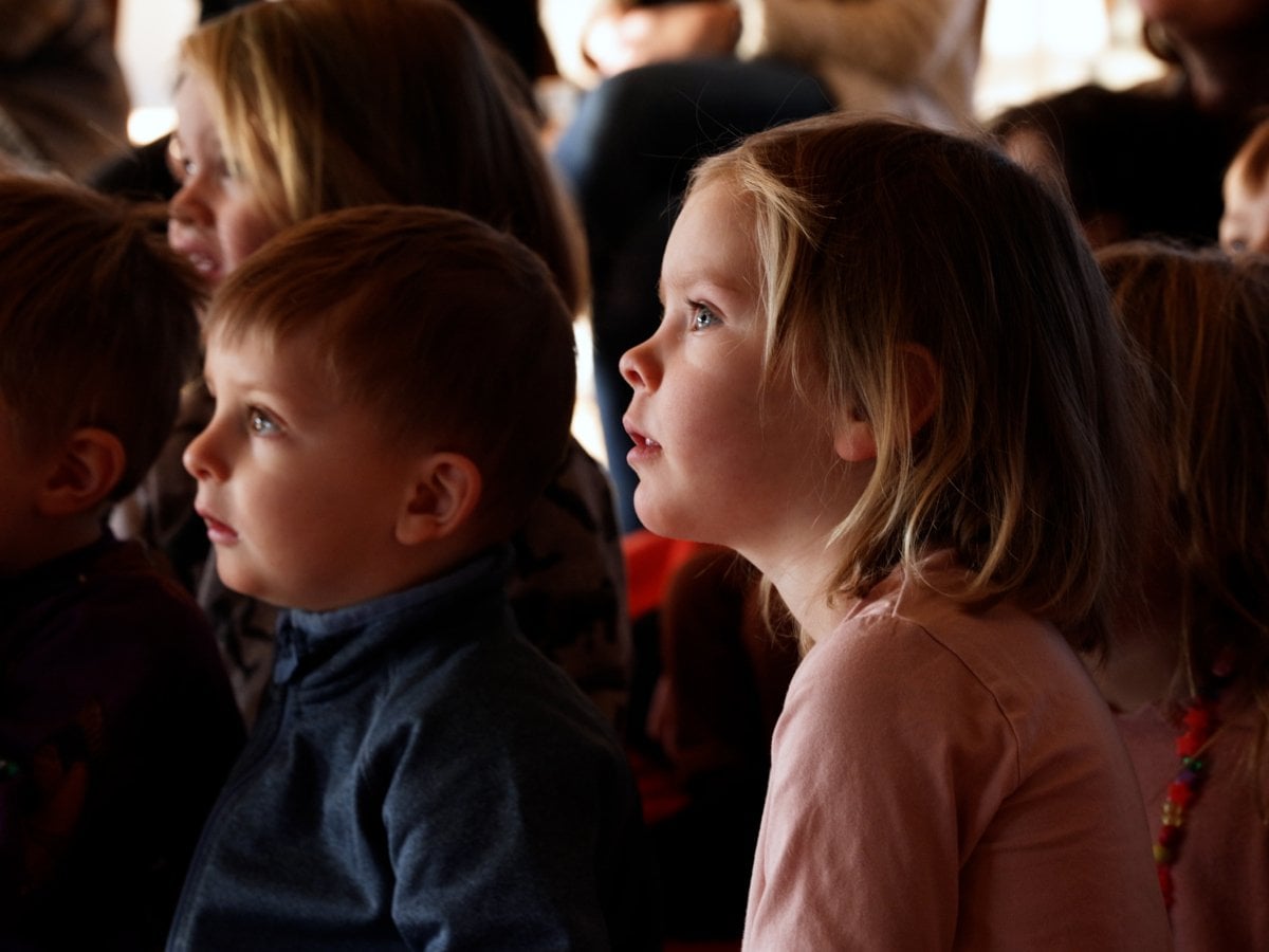 Barn som sitter och tittar koncentrerat åt samma håll (föreställningen de tittar på är utanför bilden)