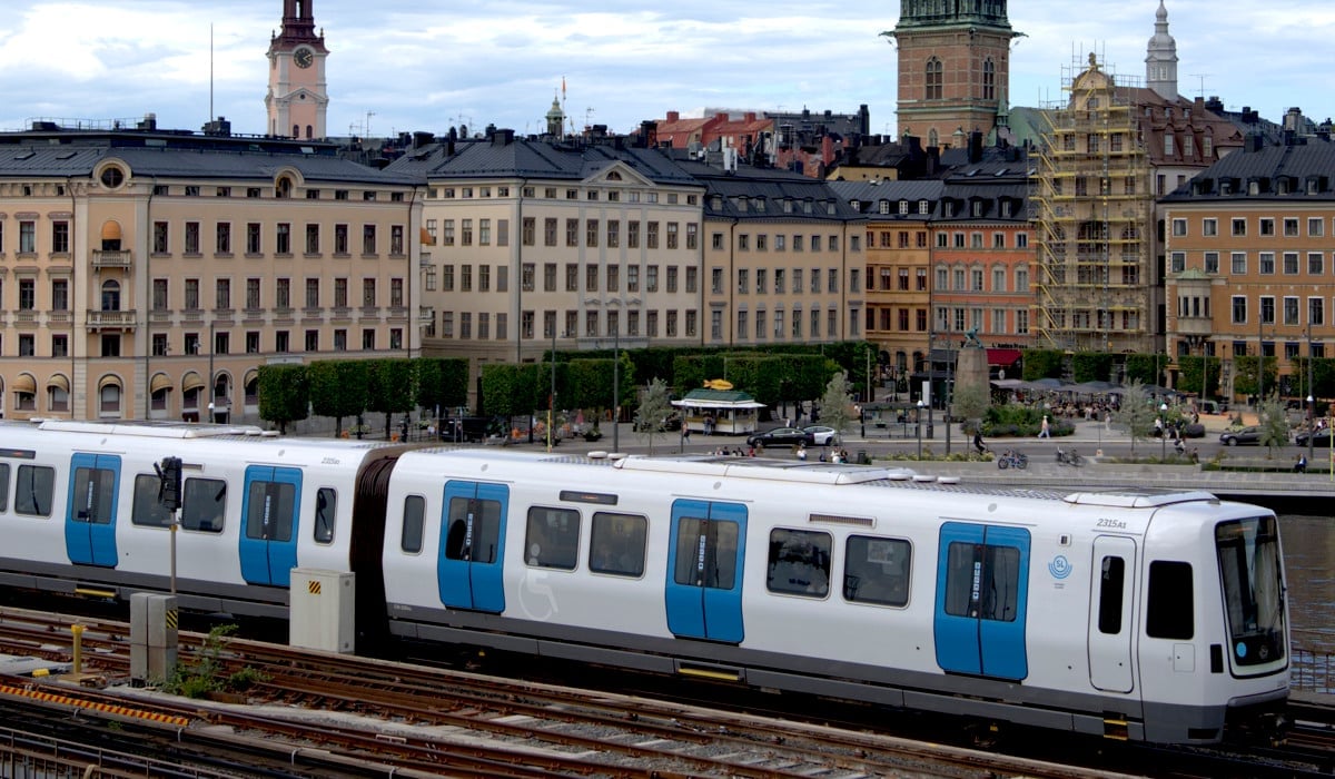 Ett vitt och blått C30-tåg som färdas på en bro förbi Gamla stan.