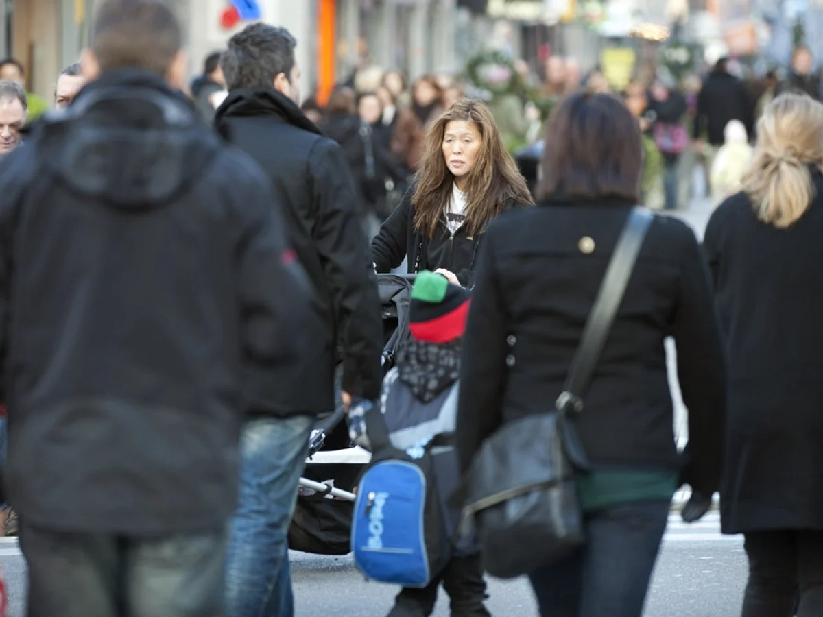 Folkvimmel på gata. I förgrunden en kvinna med barnvagn.