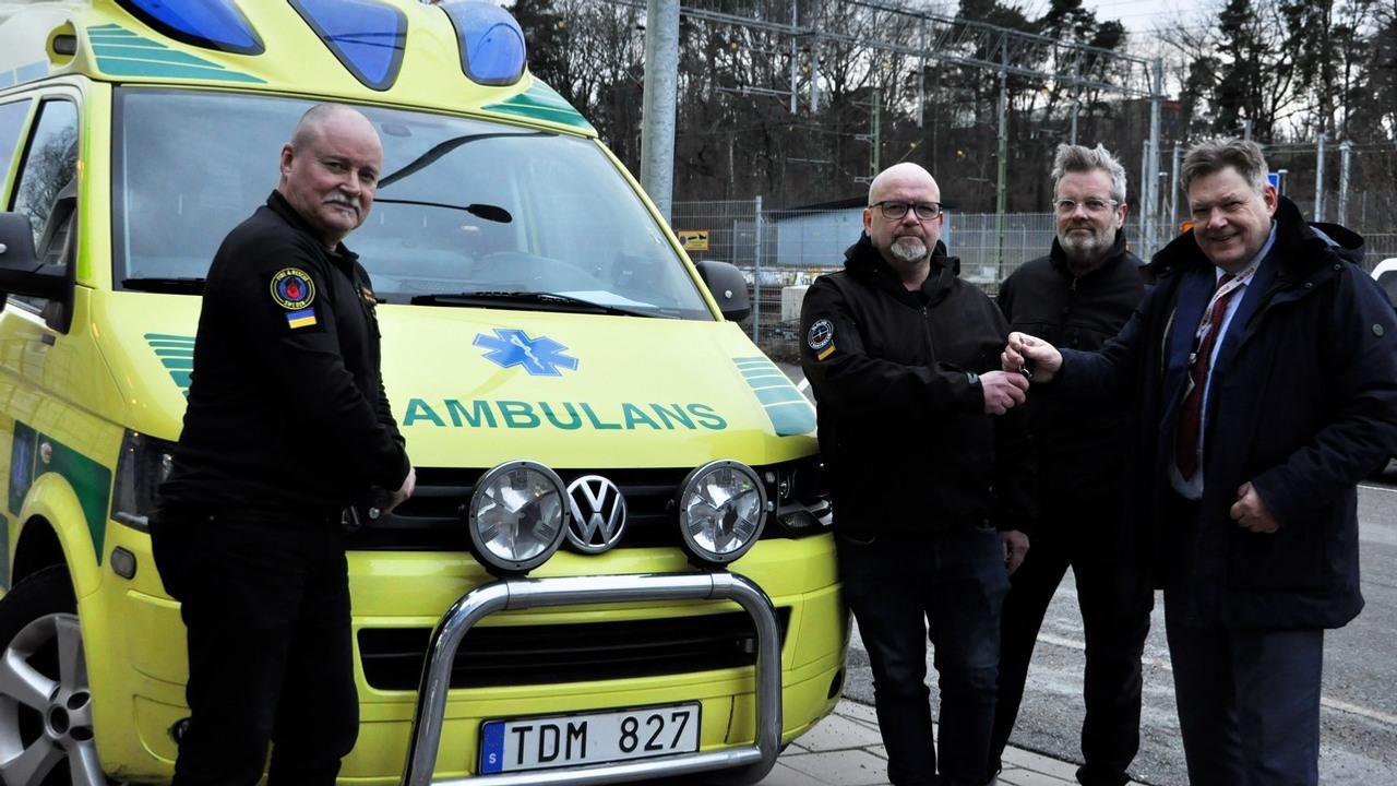 Fyra personer står framför en ambulans som ska doneras till Ukraina