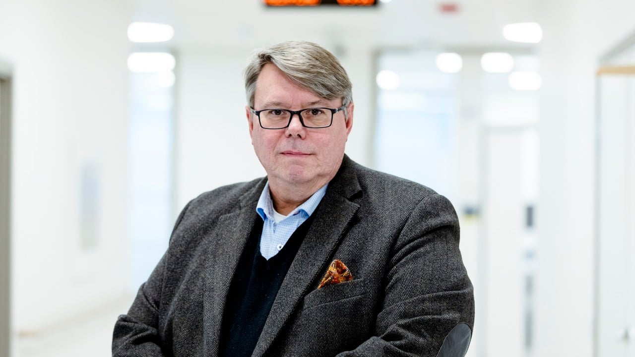 Person med glasögon i vit sjukhuskorridor