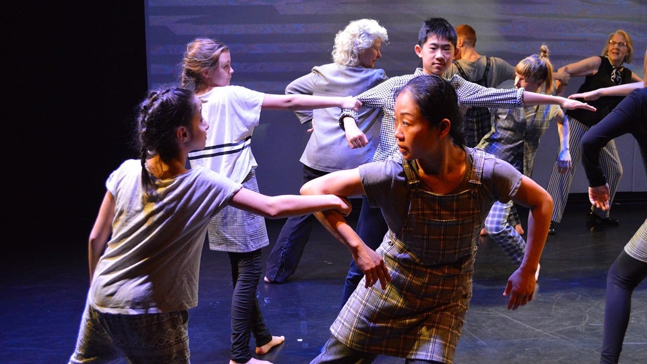 Människor i olika åldrar som dansar genom att kroka arm i varandra.