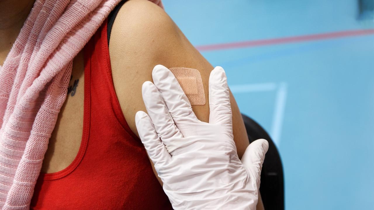 En person har precis fått vaccination mot covid-19. En hand sätter tryck mot plåstret på armen