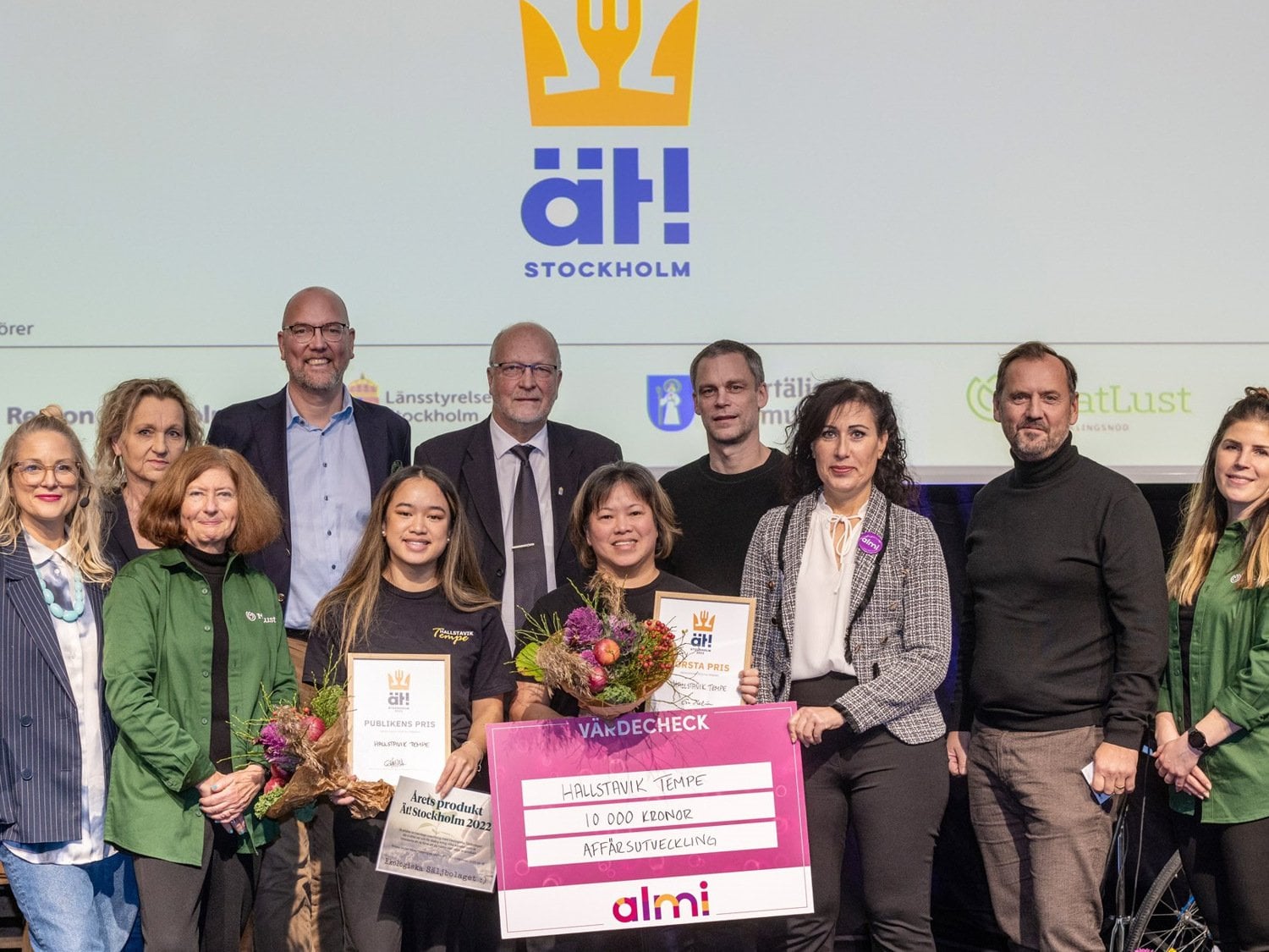 Personer som står uppradade och håller upp en rosa vinnarcheck.