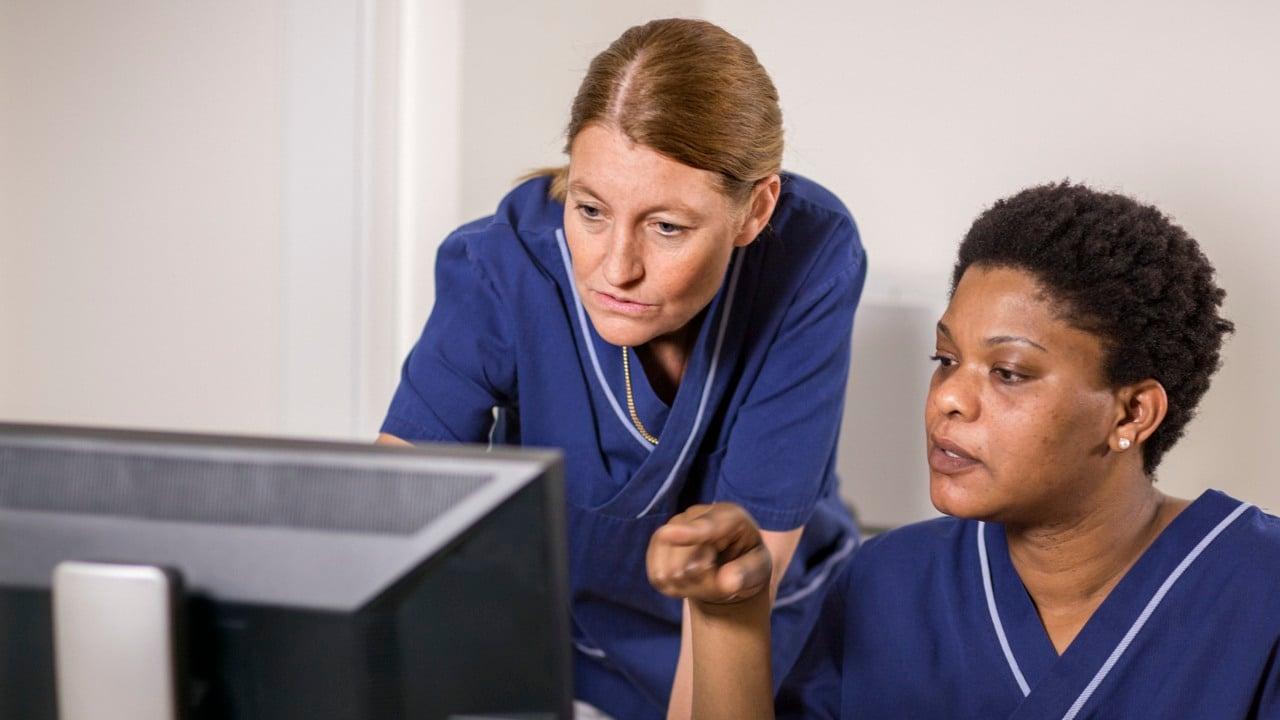 Två vårdmedarbetare tittar på en dataskärm tillsammans