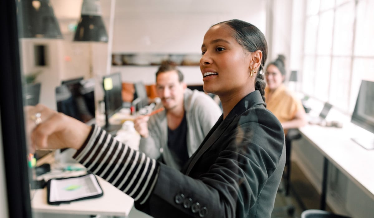 En kvinna som pekar på en skärm. I bakgrunden syns en man som tittar på skärmen.