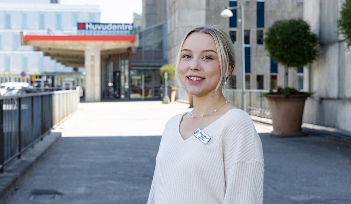 En kvinna står framför en byggnad.