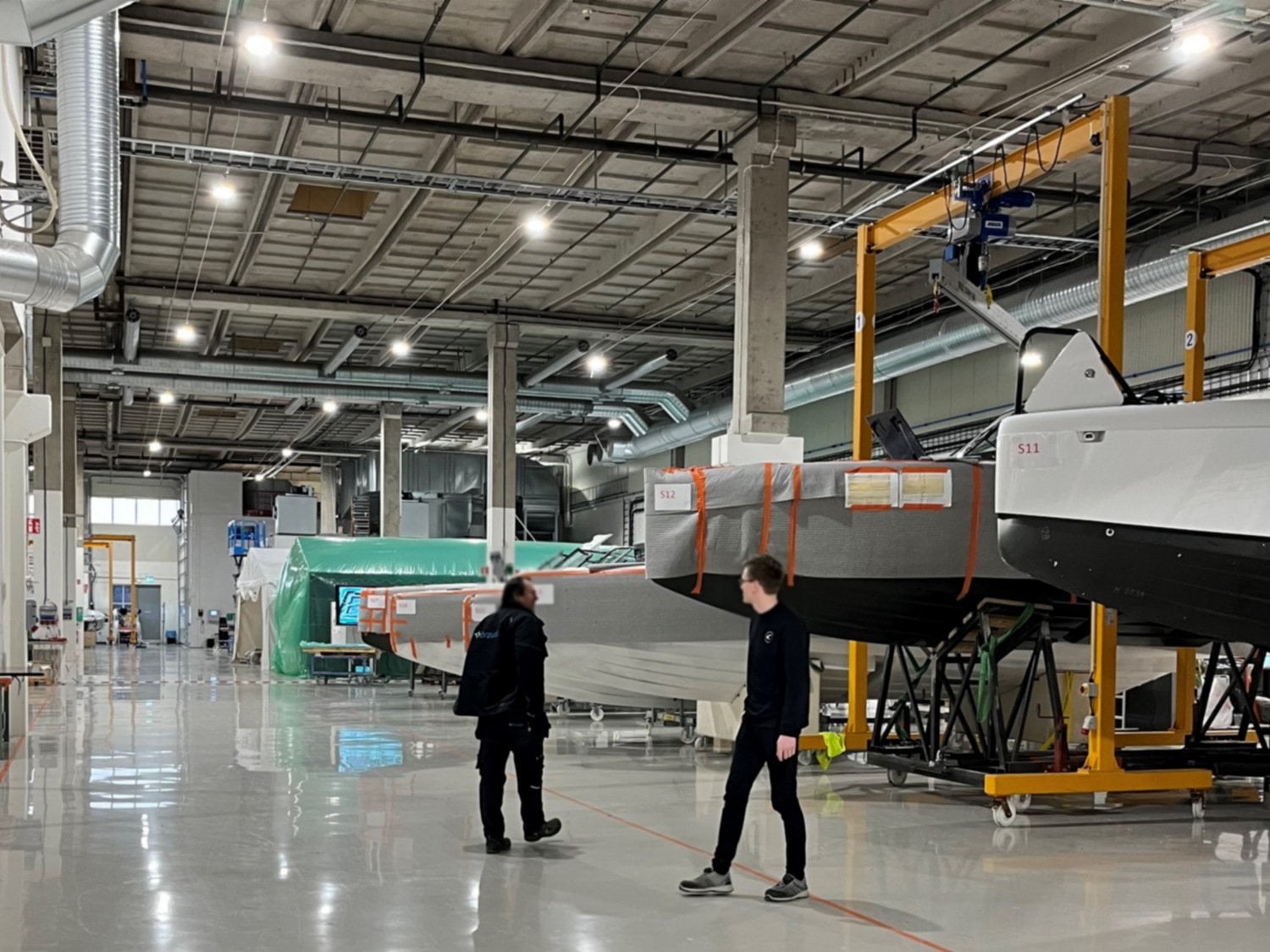 Två personer står i stor hall där båtar står på rad