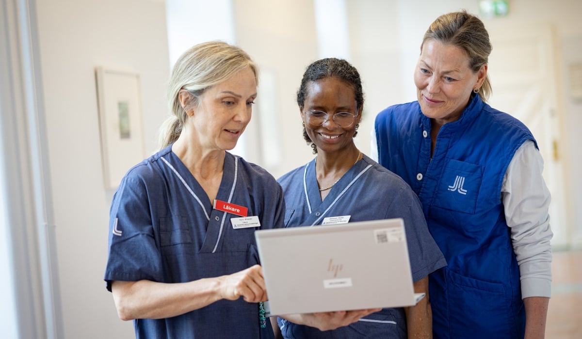 En grupp sjuksköterskor som står runt en bärbar dator.