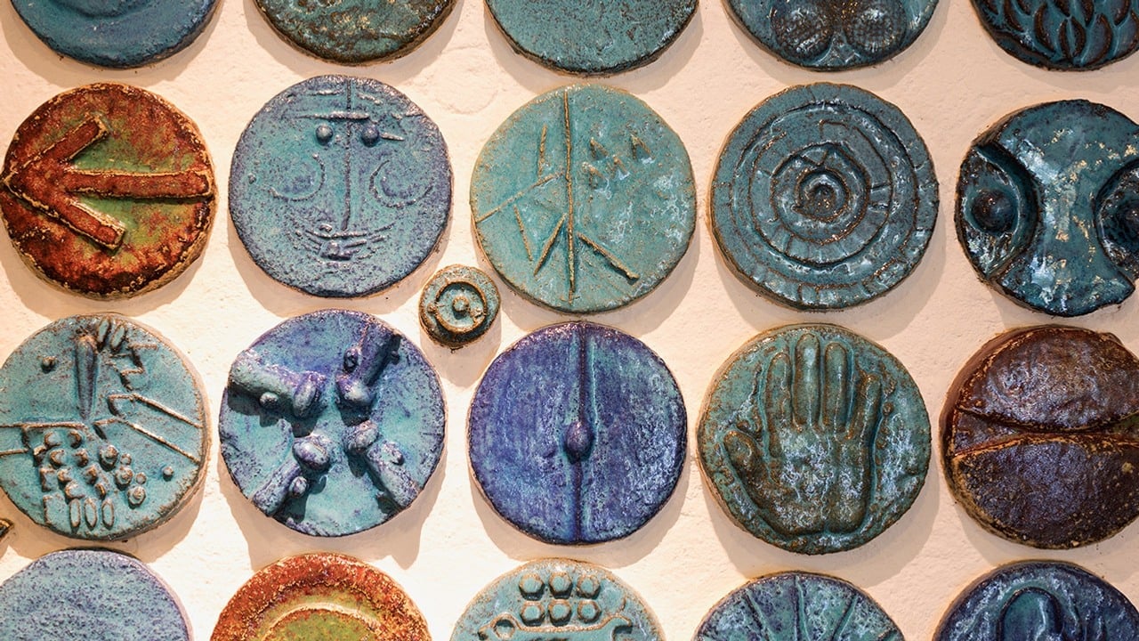 små runda keramikplattor med ansiktsmönster i flera rader