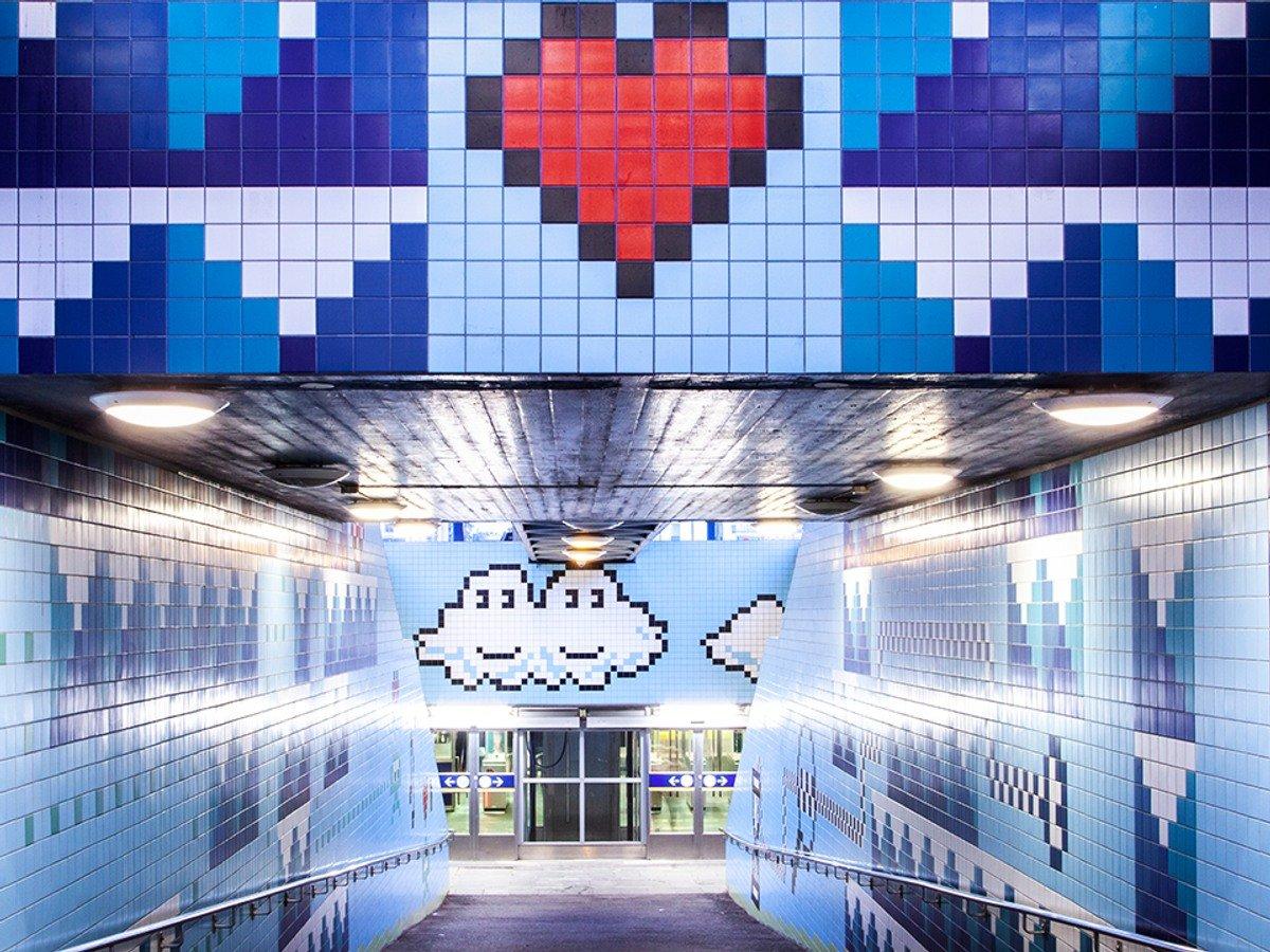 Pixlad konst som pryder Thorildsplans tunnelbana. I mitten av bilden ser vi ett rött hjärta och moln med ögon