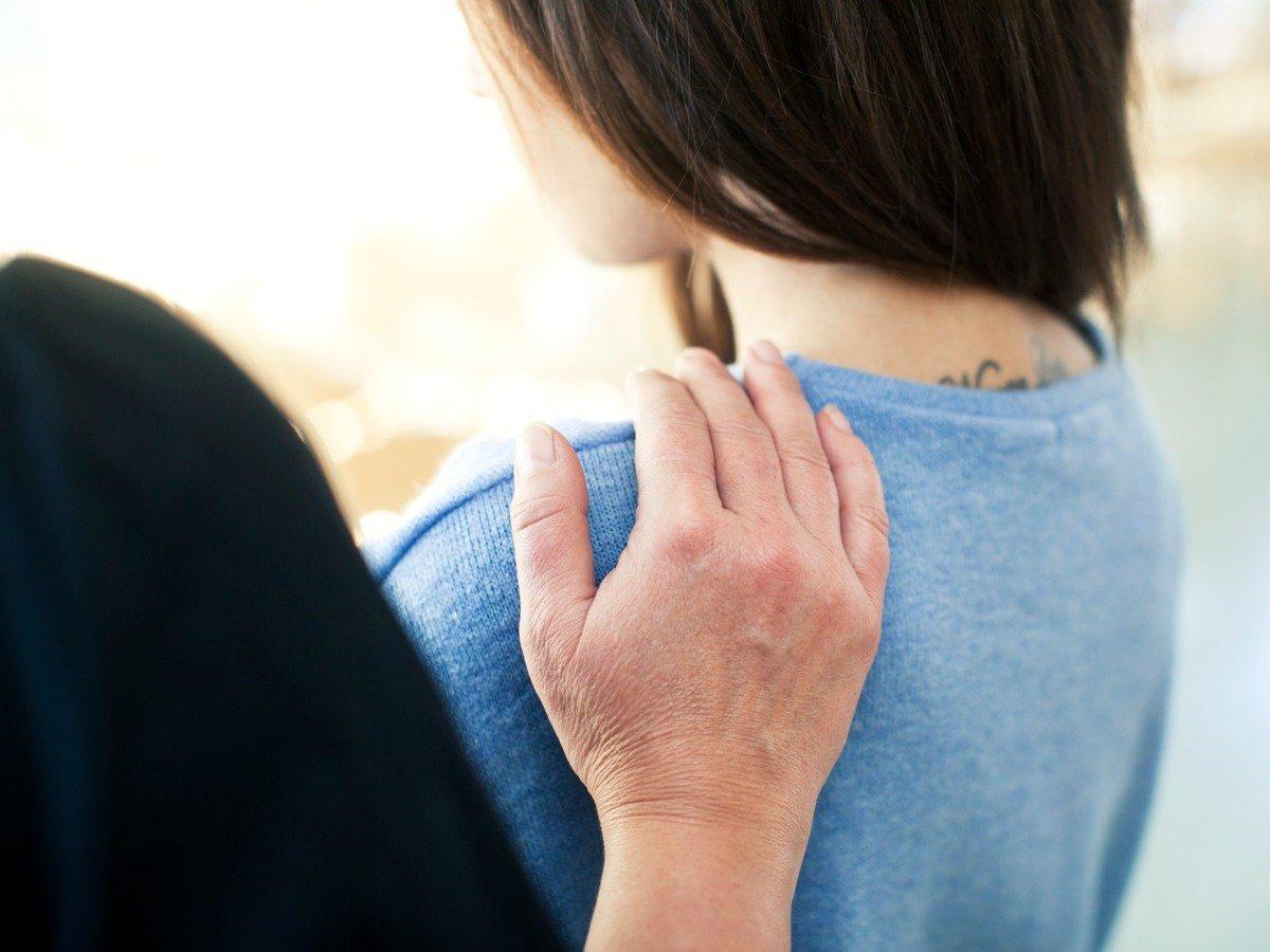 En person håller sin hand mot en kvinna axel