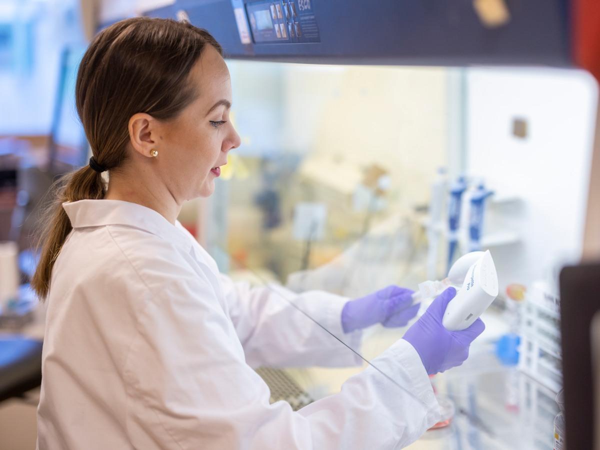 Kvinna i labbkläder som arbetar i ett laboratorium