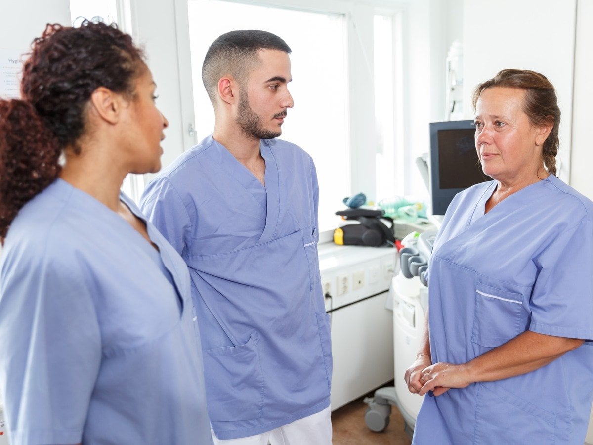 Tre medarbetare inom vården samtalar med varandra