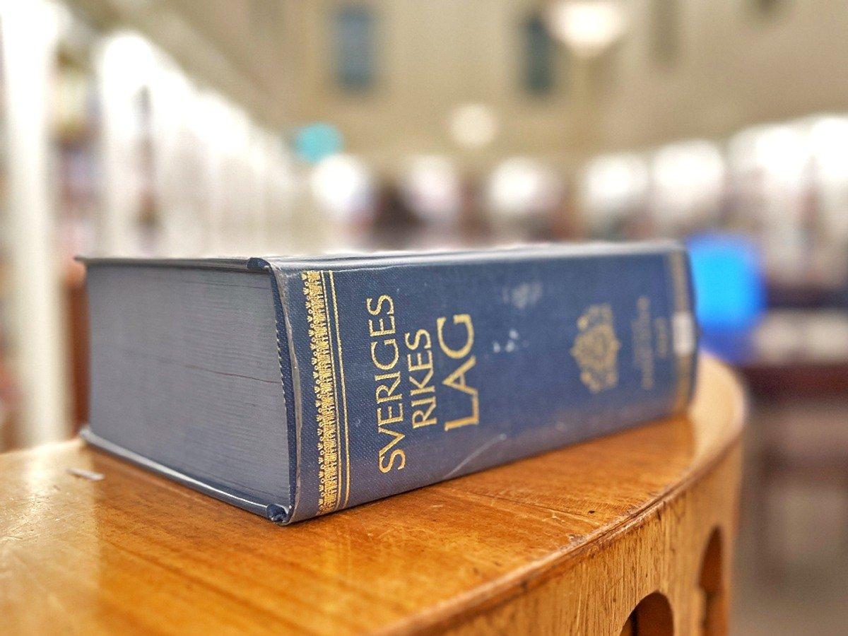 Lagboken på ett träbord. På kortsidan av boken står det "Sverige rikes lag"