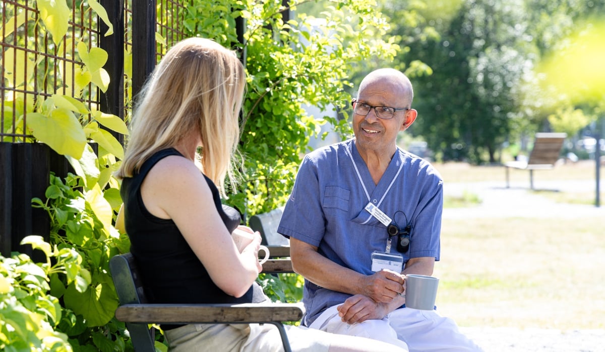 Manlig kollega sitter på en parkbänk och samtalar med en kvinna.