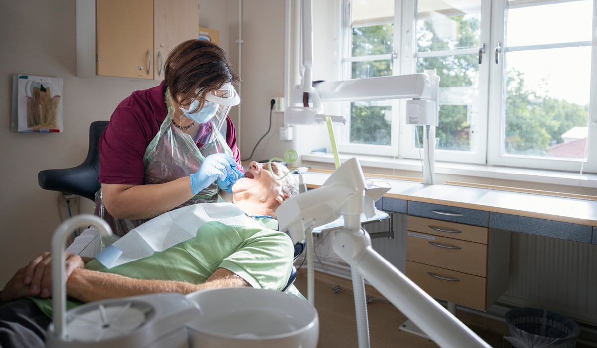 En kvinna i en tandläkarstol som får sina tänder kontrollerade.