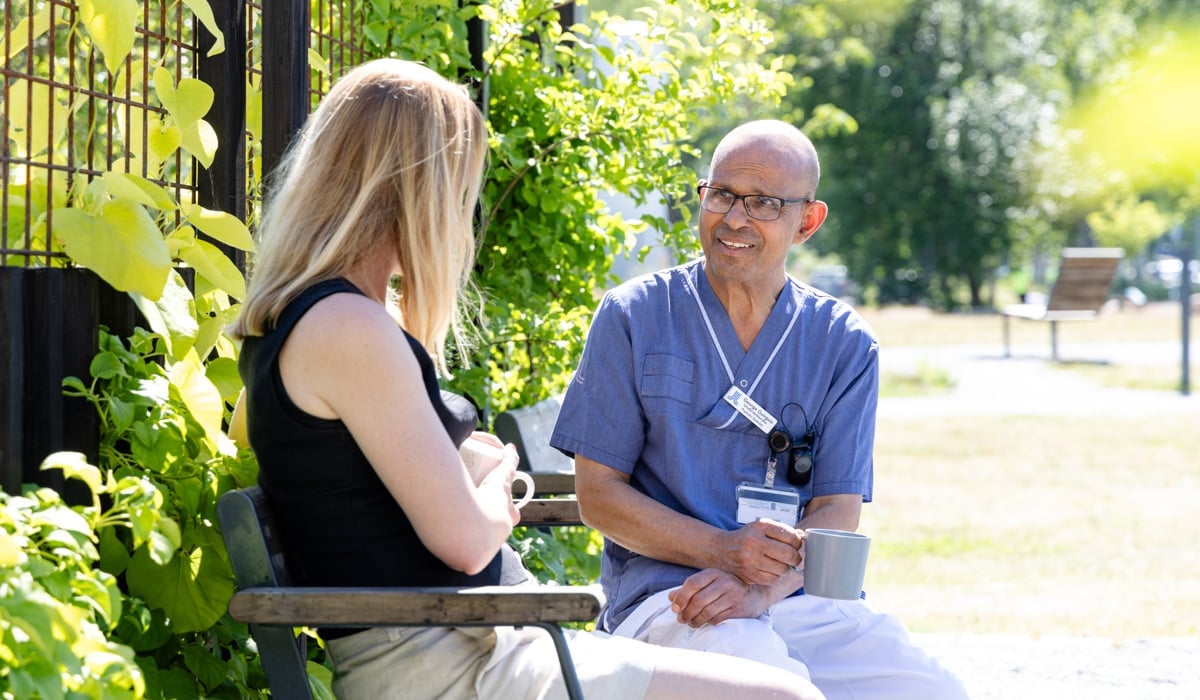 Manlig kollega sitter på en parkbänk och samtalar med en kvinna.