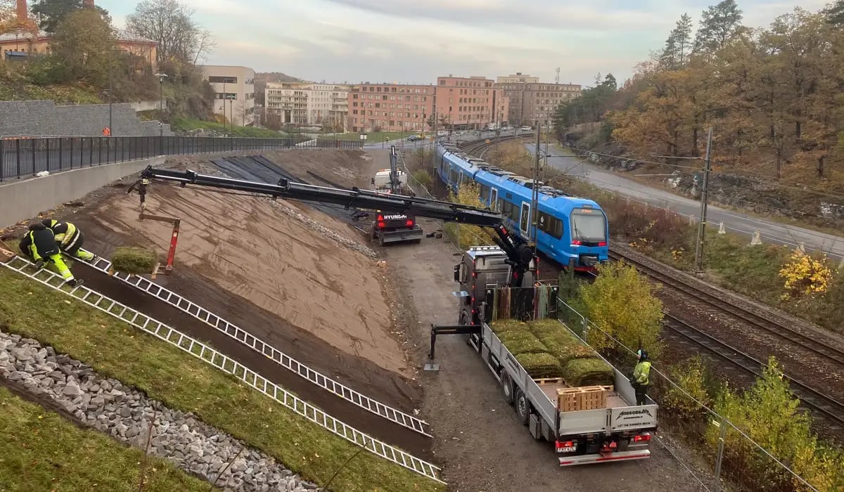 Utsikt från Ruddammsvägen vid Roslagsbanan där grön banvall anläggs i en bakslänt till Roslagsbanan