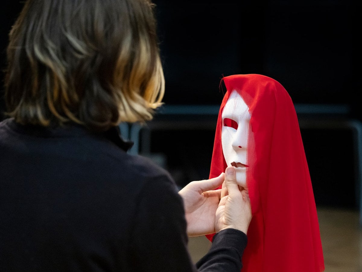 Person håller en teatermask framför sig.