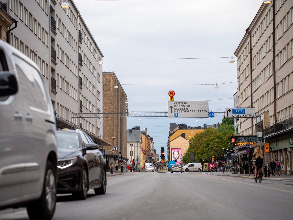 En bil som kör längs en gata bredvid höga byggnader.