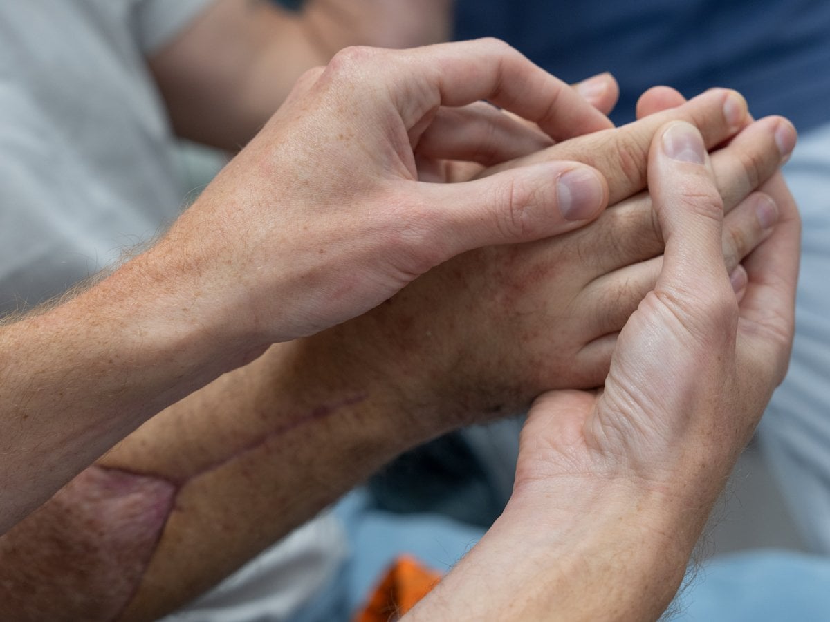 Två händer masserar en tredje hand.