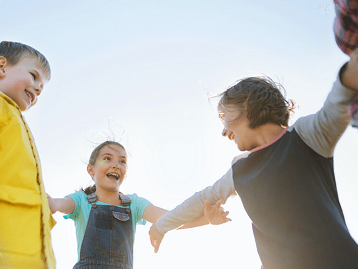 Foto på flera barn som står i en ring och håller varandra i händerna.