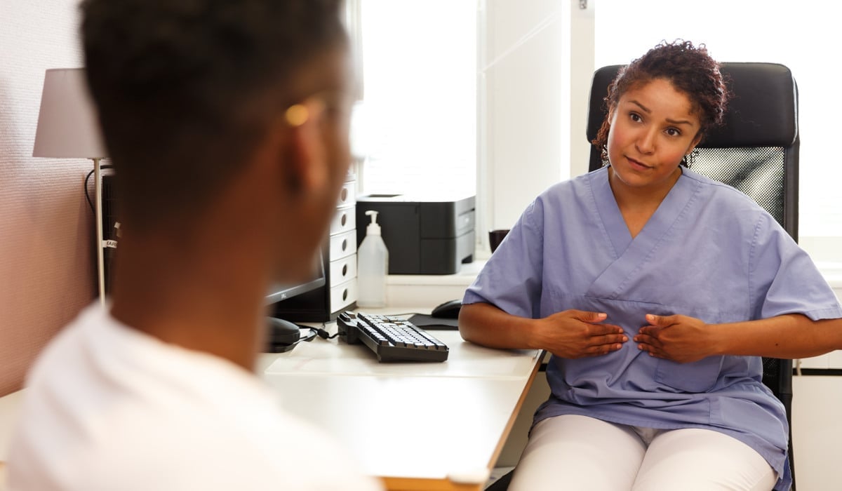 En kvinna i operationskläder sitter vid ett skrivbord.