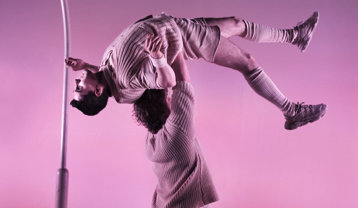 Foto från en cirkus. En person lyfter en annan person över huvudet.