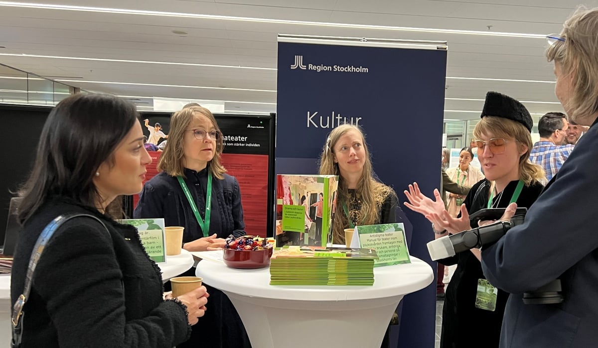 Människor samlas runt ett bord och samtalar och gestikulerar.