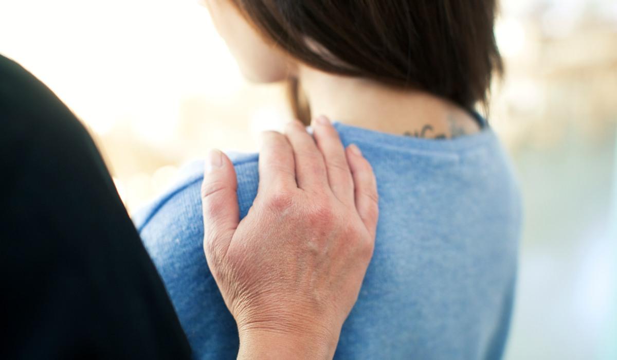 En hand på en kvinnas axel