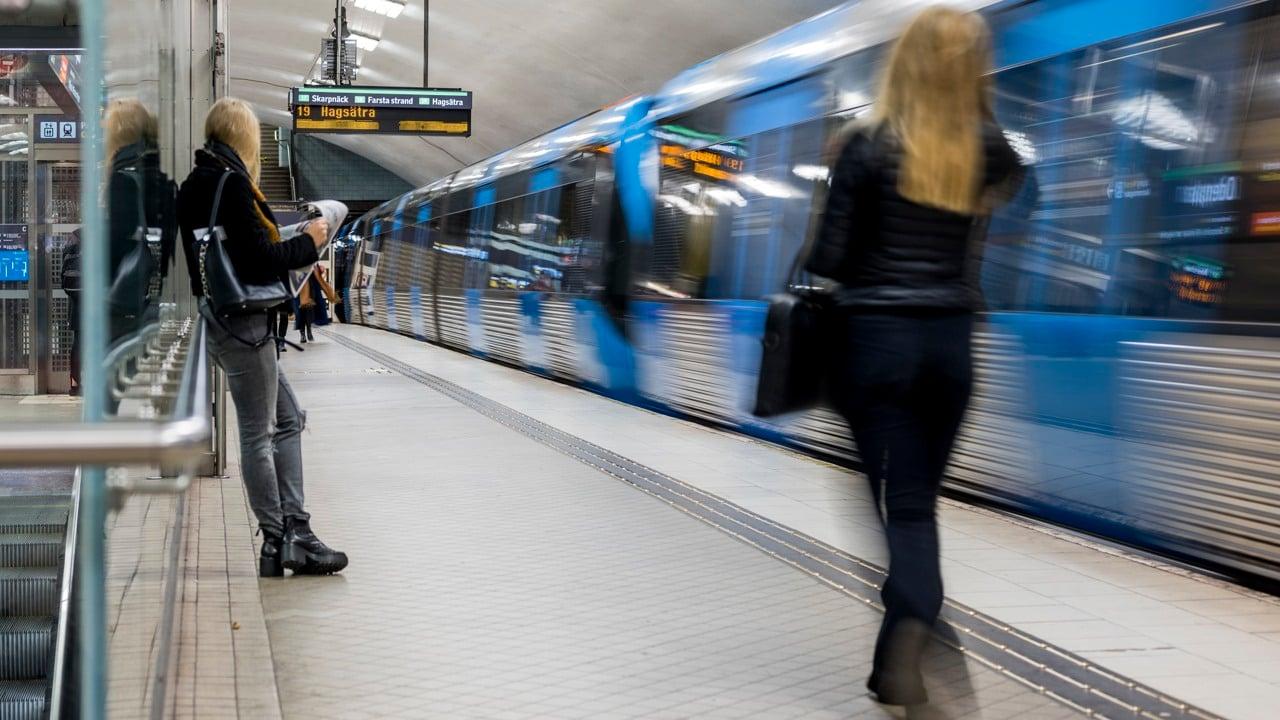 Personer väntar på tunnelbanan som rullar in i hög fart