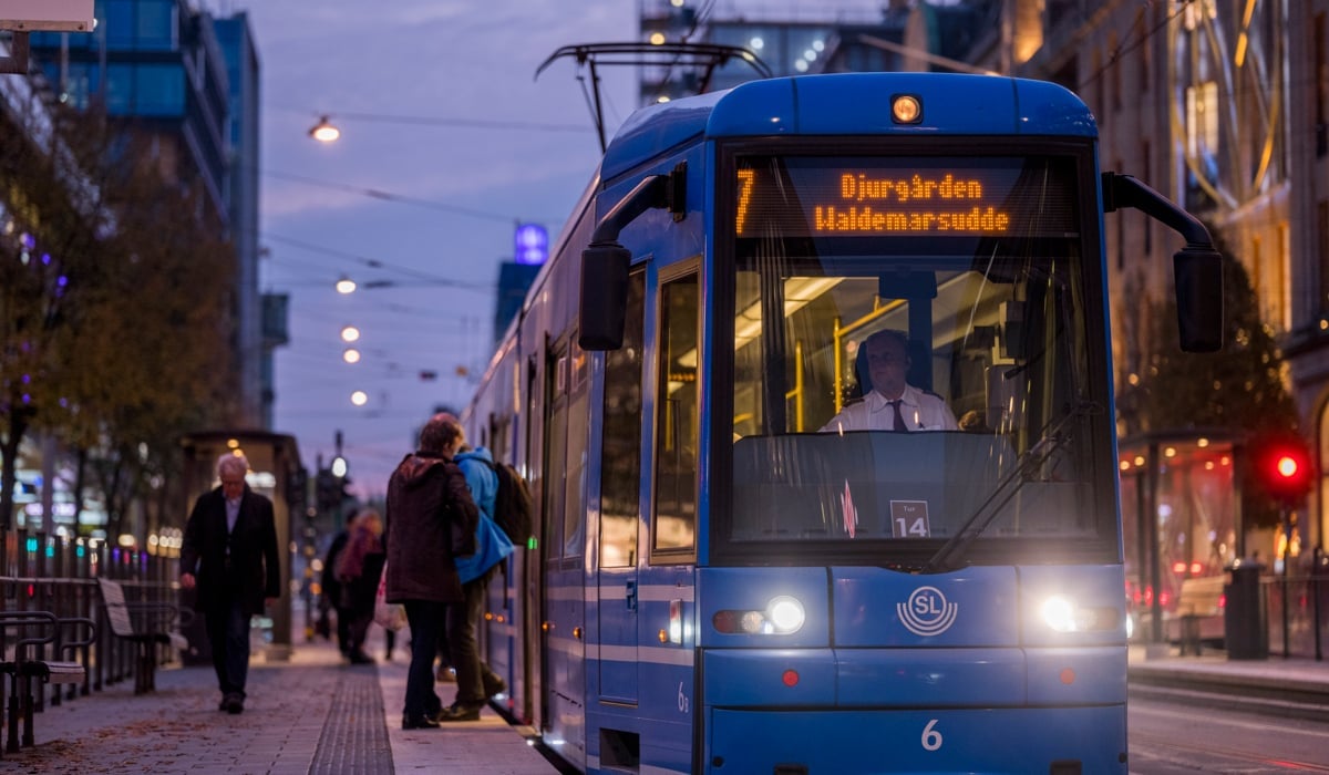 Spårvagn avgår utanför Stockholm. Det är solnedgång och himlen är rosa.